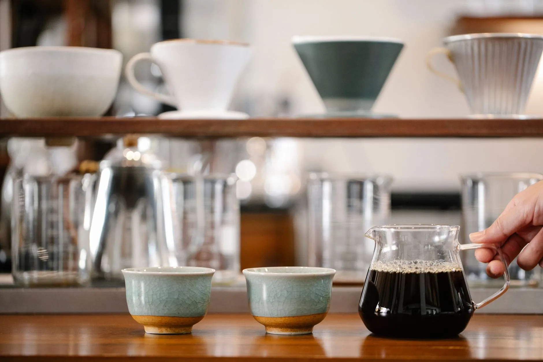 Two ceramic cups and a glass server of filter coffee on the café counter